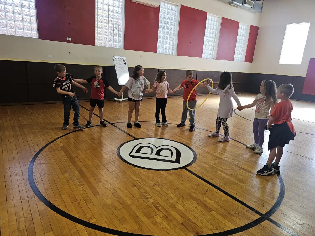 Students playing with hula hoops during PE class in the gymnasium