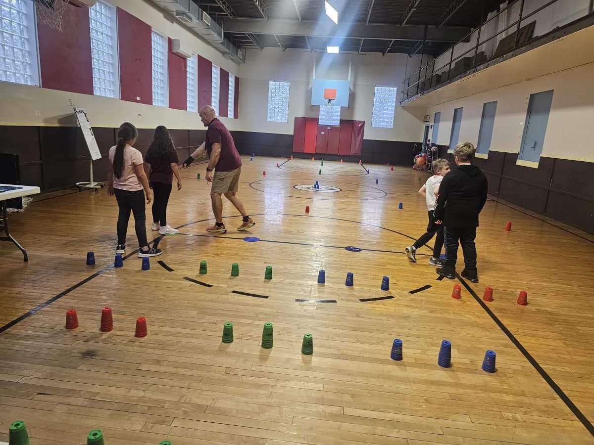 Students playing a cup stacking game during PE in the gymnasium