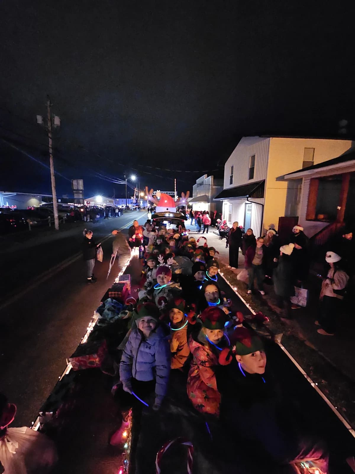 Students riding on a decorated float during the Elkins Christmas parade at night