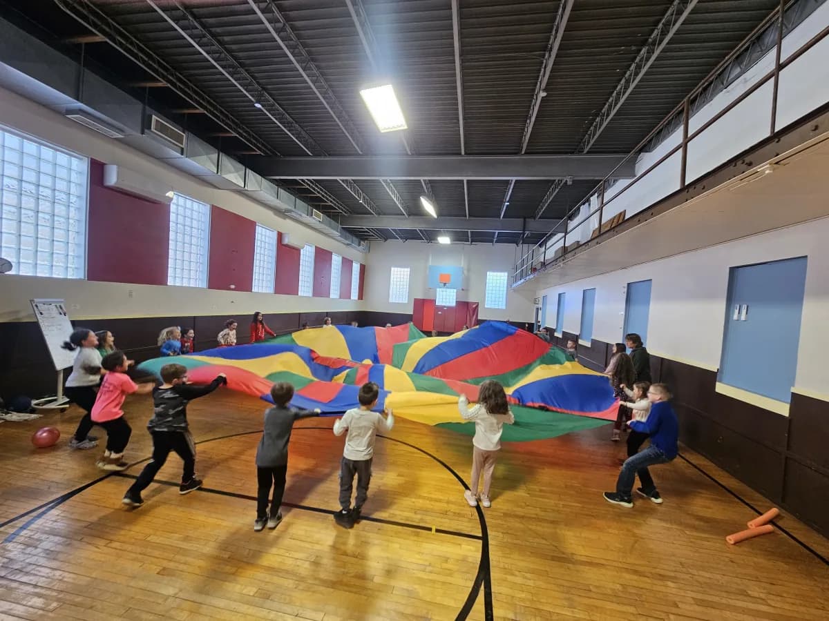 Students playing parachute games together in the gymnasium during PE