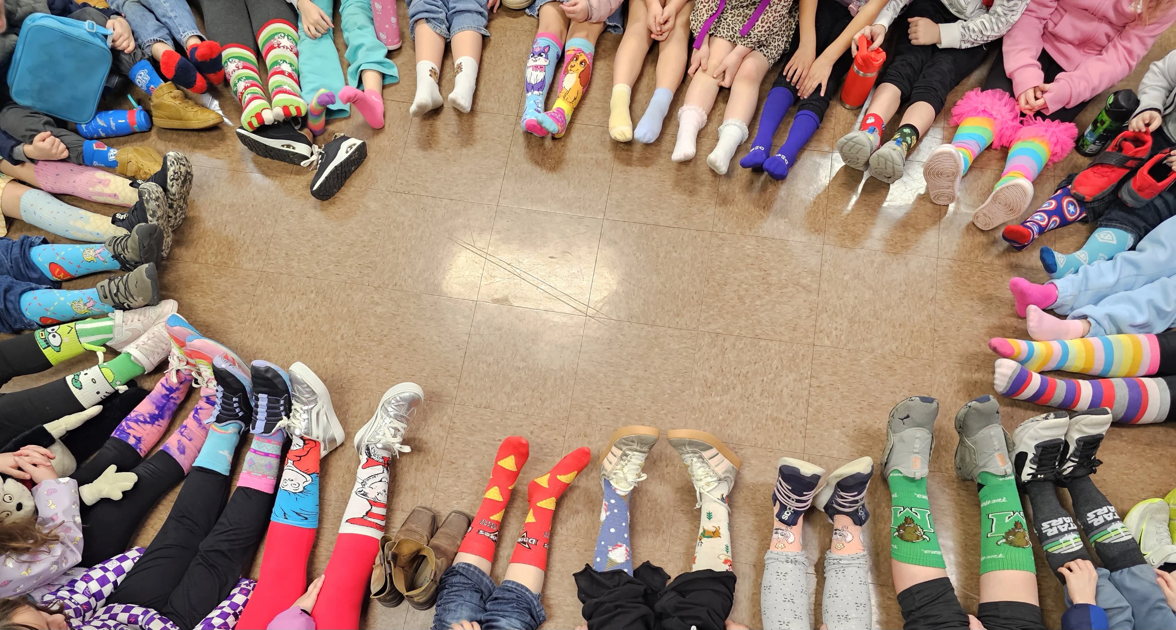 Students showing off colorful mismatched socks arranged in a circle during Crazy Sock Day