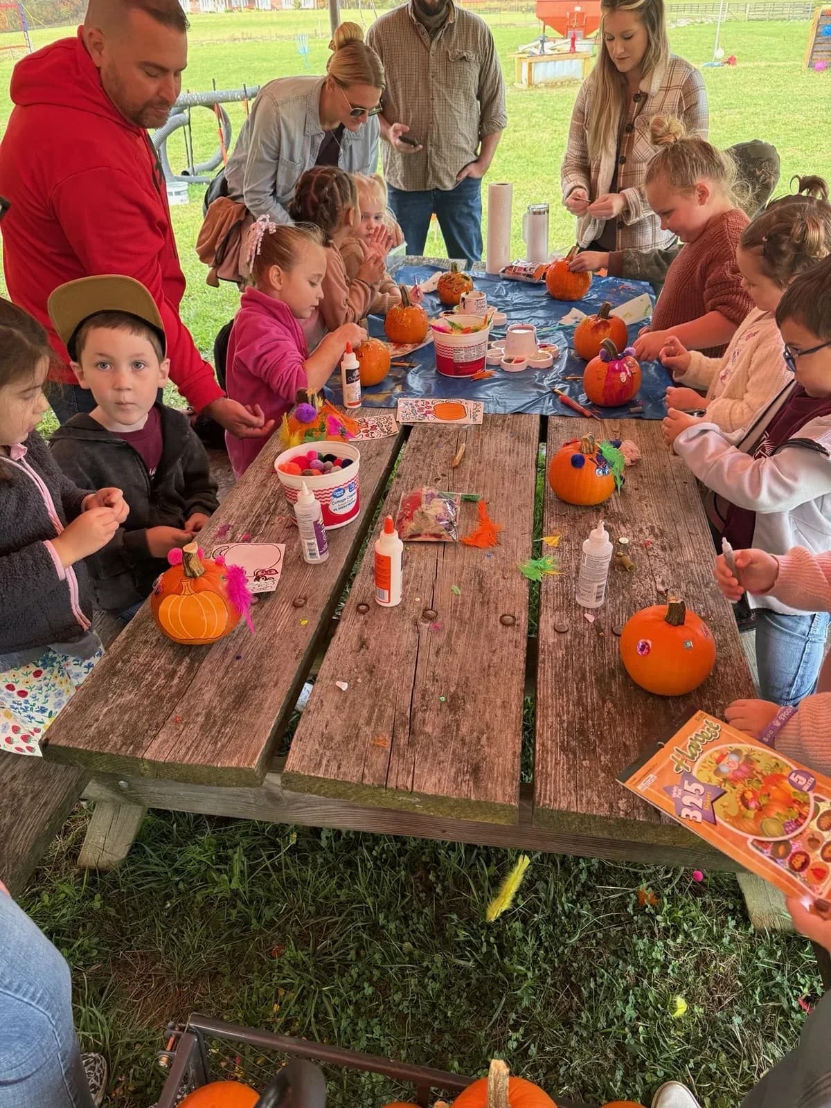 Students and parents decorating pumpkins at an outdoor fall activity