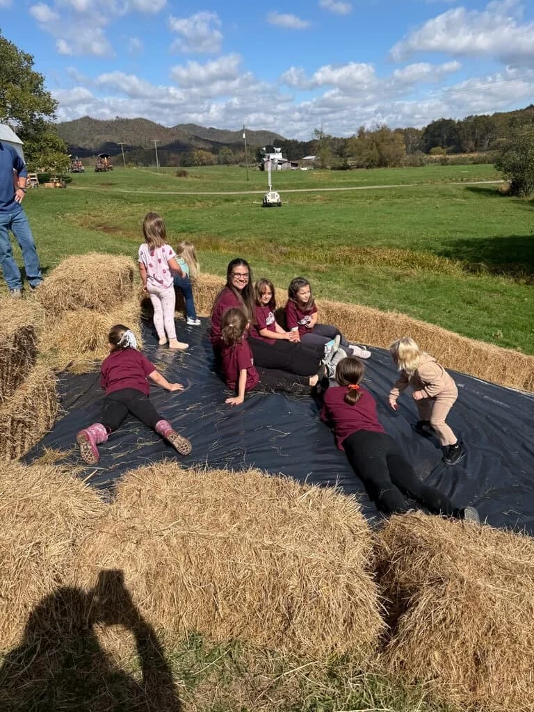 Students playing on hay bales during the fall field trip